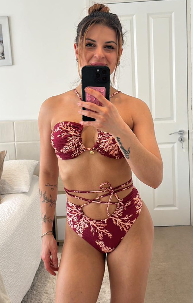 Woman taking a mirror selfie wearing a red bikini in a bedroom.